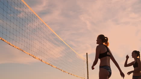 Sexy-volleyball-girls-in-bikini-play-on-the-beach-in-summer-volleyball-on-the-sand-at-sunset-in-slow-motion